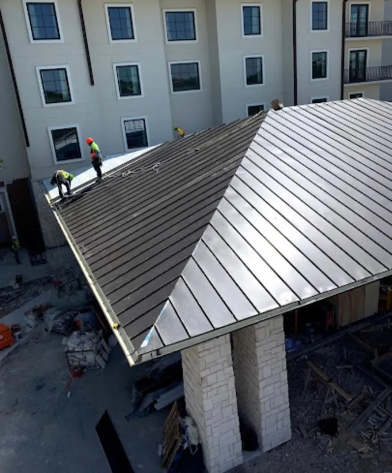 Crew installing standing seam metal roof panels on a commercial project in Barnstead
